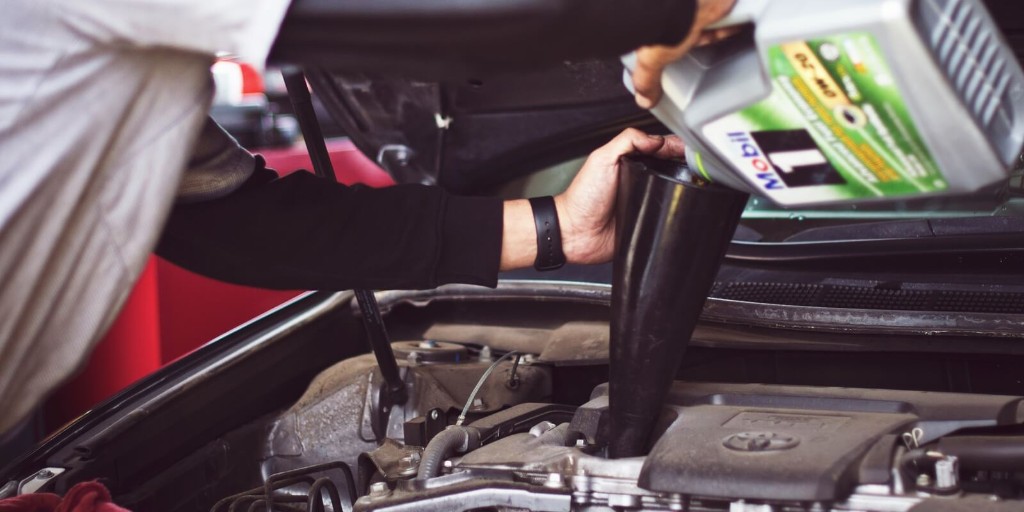 Technician pouring premium motor oil during a service