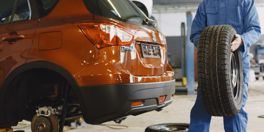 Mechanic fitting a new tire on a lifted vehicle